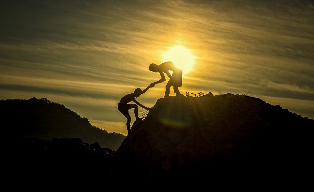 gtc helping hands of two people climbing a mountain together