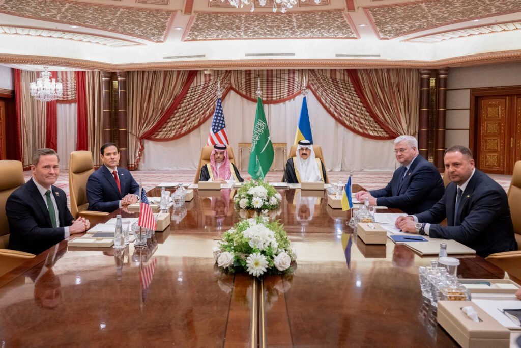 several men sitting around a table with flags on the walls